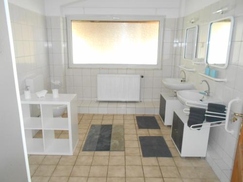 La salle de bains blanche est pourvue d'un lavabo et de toilettes. dans l'établissement Moorberghof, à Sagau