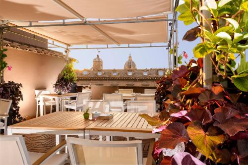 a restaurant with white chairs and tables and plants at Hotel Indigo Rome - St. George by IHG in Rome