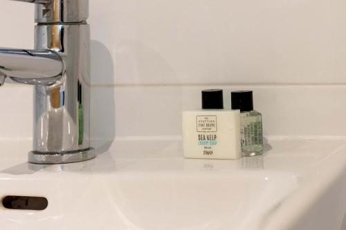 a bathroom sink with two bottles of soap on it at The Portland Penthouse - Donnini Apartments in Troon
