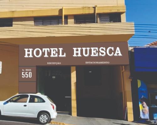 a white car parked in front of a hotel hiscaza at Hotel Palace Huesca in Presidente Prudente