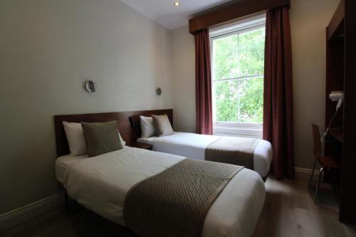a hotel room with two beds and a window at Wedgewood Hotel in London