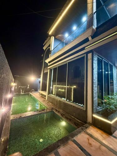 a house with a swimming pool at night at Twilight Stays ll R Villa 3BHK ll Swimming Pool ll AC ll BBQ in Lonavala
