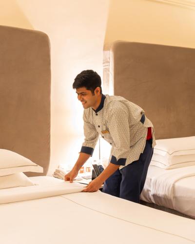 a man making a bed in a bedroom at Taj Deccan in Hyderabad