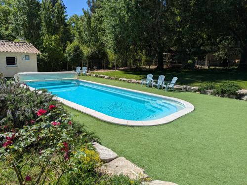 a swimming pool with two chairs in a yard at Mobil home climatisé avec piscine in Viviers