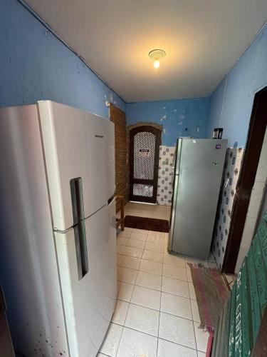 a kitchen with a white refrigerator and blue walls at Hostel Casa Jambo Guaruja in Guarujá