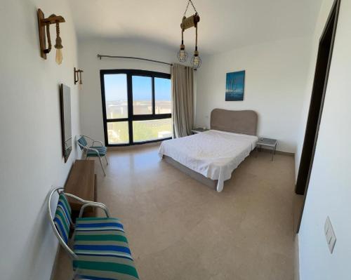 ein Schlafzimmer mit einem Bett und einem großen Fenster in der Unterkunft Swanlake Lagoon Luxury Villa in Zāwiyat al ‘Awwāmah