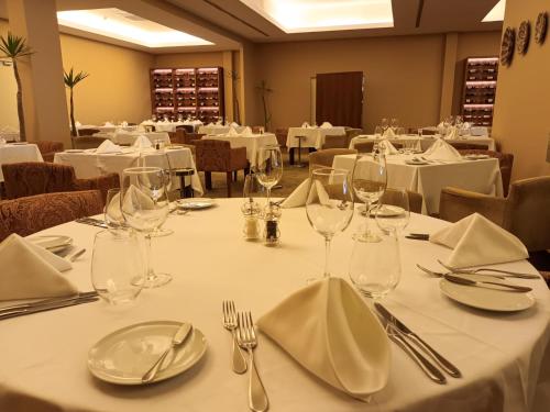 a dining room with white tables with glasses and napkins at AP Lago Montargil - Conference & SPA in Montargil