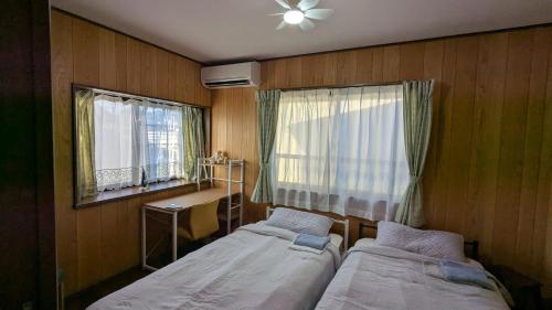 a small room with two beds and a window at いちごハウス in Zushi
