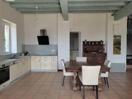 a kitchen with a wooden table and white chairs at Le Pavillon du château de Jean 