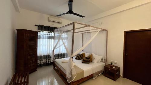 ein Schlafzimmer mit Himmelbett und Fenster in der Unterkunft Wind Haven Yala in Tissamaharama