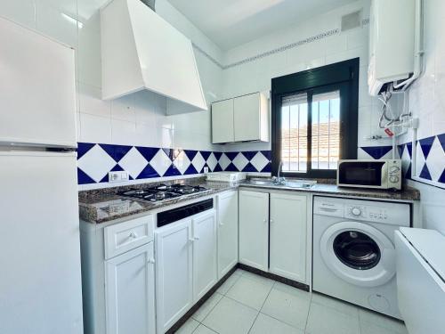 a kitchen with white cabinets and a washer and dryer at Apartamentos Turísticos Santo Rostro in Chipiona