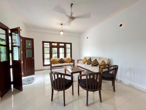 ein Wohnzimmer mit Tisch und Stühlen und einer Couch in der Unterkunft Wind Haven Yala in Tissamaharama
