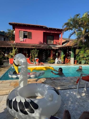 a swan in a swimming pool next to a house at Hostel Casa Jambo Guaruja in Guarujá