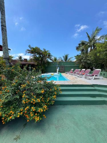 a swimming pool with chairs and flowers next to it at Hostel Casa Jambo Guaruja in Guarujá