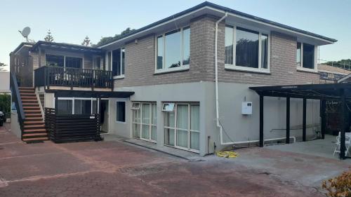 a house with a balcony and a staircase in front of it at Coastal Retreat in Wellington - Perfect for Quick Stays in Wellington