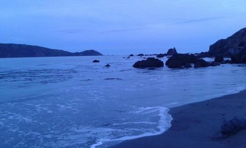 a beach with rocks in the water and the ocean at Coastal Retreat in Wellington - Perfect for Quick Stays in Wellington