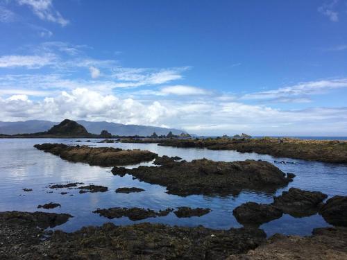 a large body of water with rocks and mountains at Coastal Retreat in Wellington - Perfect for Quick Stays in Wellington