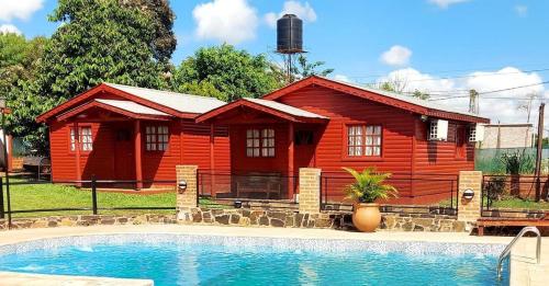 a log cabin with a swimming pool in front of a house at Portal del sol in Puerto Iguazú