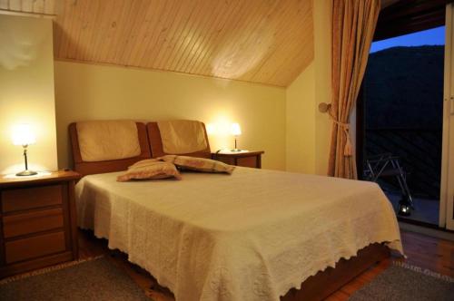 a bedroom with a bed with two lamps and a window at casa do meio da vila suites in Loriga