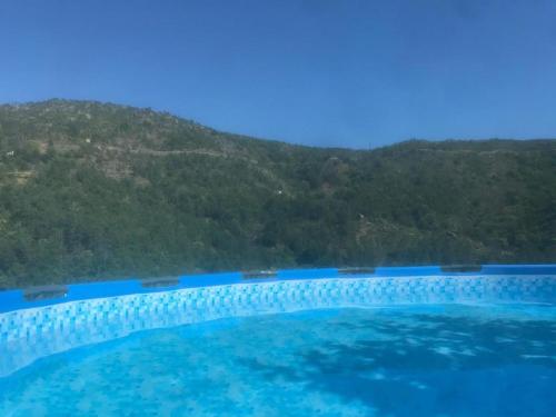 a large swimming pool with a mountain in the background at casa do meio da vila suites in Loriga