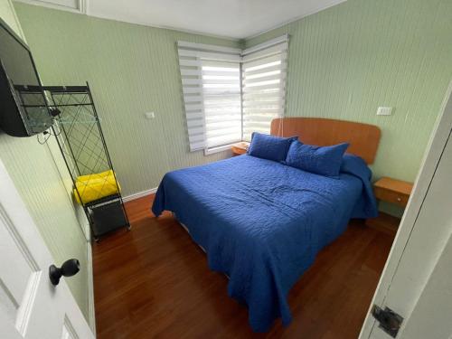 ein Schlafzimmer mit einem Bett mit blauen Laken und einem Fenster in der Unterkunft Cabaña El Retiro in Lebu