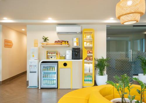 a room with a refrigerator and a yellow couch at Bloom Boutique l Sector 45 Gurugram in Gurgaon
