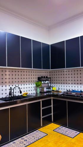 a kitchen with dark blue cabinets and a sink at Arrafah Homestay Klebang in Tranquerah