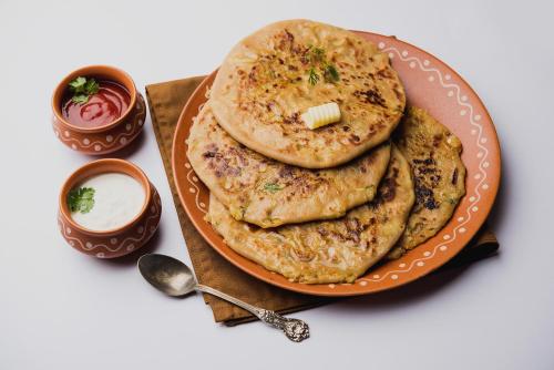 a plate of naan bread with sauce and dip at Super Hotel O Chhatarpur Formerly Royal Galaxy in New Delhi