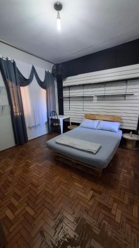 a bedroom with a large bed and a wooden floor at Rota Mundus Turismo e Hospedagem in Botucatu