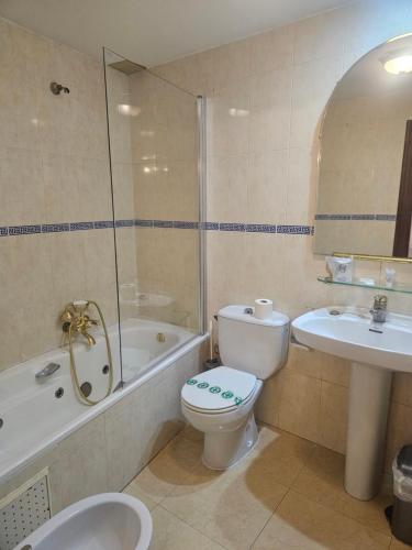 a bathroom with a toilet and a tub and a sink at Hosteria Real de Zamora in Zamora