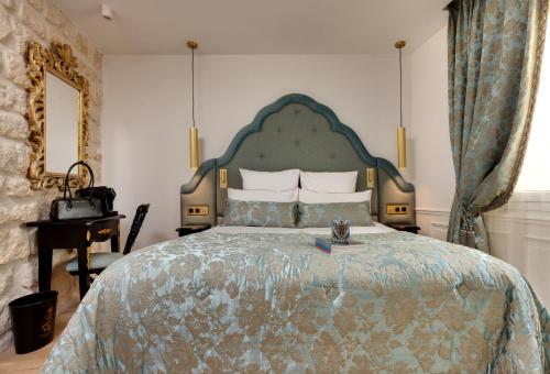 a bedroom with a large bed with a green headboard at Hôtel Kleber Paris & Spa in Paris