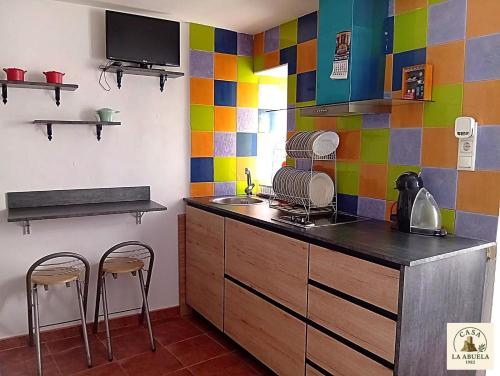 a kitchen with colorful tiles on the wall and two chairs at Casa La Abuela 1982 in La Iruela