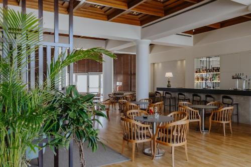 a restaurant with tables and chairs and plants at Golden Coast Beach Hotel in Protaras