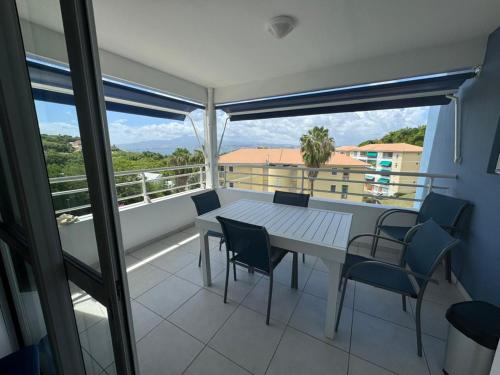 a table and chairs on a balcony with a view at La perle de l anse in Les Trois-Îlets