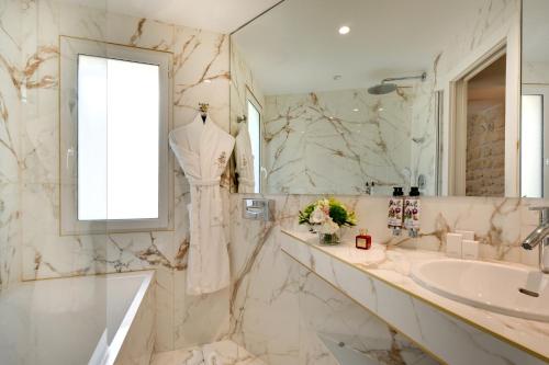 a bathroom with a sink and a tub and a mirror at Hôtel Kleber Paris & Spa in Paris