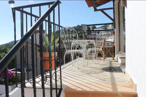 a balcony with white chairs and a table and chairs at Horta Do Zé Miguel in Monchique