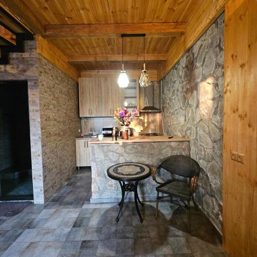 a kitchen with a table and a stone wall at Iveria Parky and cottages in Shekvetili