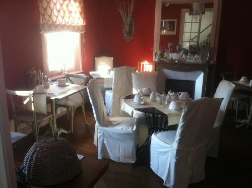 a dining room with white tables and white chairs at O Mylle Douceurs in Le Crotoy