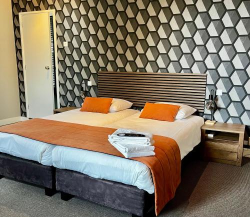 a bedroom with a large bed with orange pillows at Hotel restaurant De Roode Leeuw in Terborg