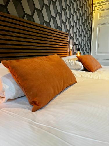 a bed with an orange pillow on top of it at Hotel restaurant De Roode Leeuw in Terborg