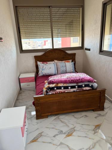 a bedroom with a wooden bed with a window at Houssam immobilier 7 in Souira Guedima