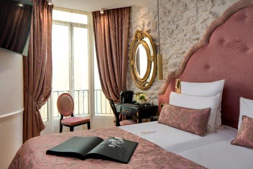 a bedroom with a bed with a book on it at Hôtel Kleber Paris & Spa in Paris