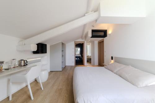 a white bedroom with a white bed and a desk at Hotel Lago Di Garda in Nago-Torbole