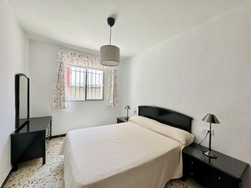 a white bedroom with a large bed and a window at Apartamentos Turísticos Santo Rostro in Chipiona