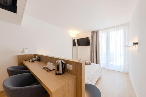 a hotel room with a bed and a desk and chairs at Hotel Lago Di Garda in Nago-Torbole