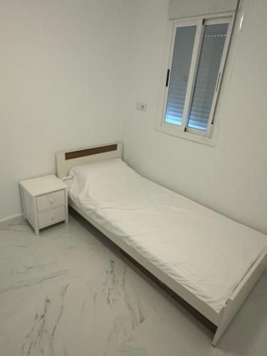 ein weißes Zimmer mit zwei Betten und einem Fenster in der Unterkunft Casablanca in Benicarló