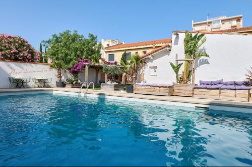a swimming pool in front of a house at Hôtel Les Sables - Urban Style - by Logis Hotels in Canet-en-Roussillon