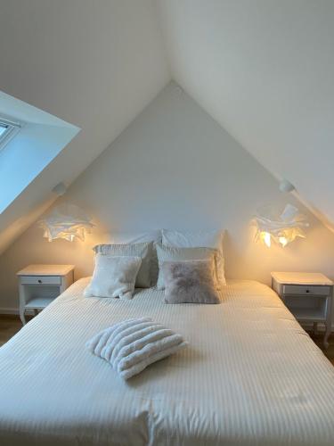 a bed with white sheets and pillows in a attic at L'Opale des Tribus in Audresselles