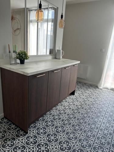 a bathroom with a sink and a mirror on a floor at La longère Cosy & Centrale in Bétheny