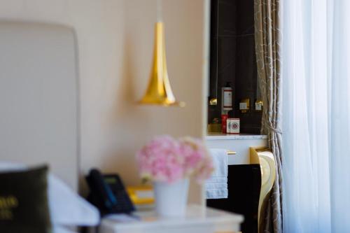 a room with a table with a vase of pink flowers at Boscolo Lyon Hotel & Spa in Lyon
